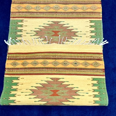Sale Photo Thumbnail #424: Handwoven Southwestern or Native American style flatweave area rug featuring geometric patterns and fringed edges in muted green, terracotta, and beige tones.