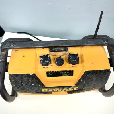 Sale Photo Thumbnail #910: DeWalt rugged jobsite AM/FM radio with heavy-duty protective roll cage and telescoping antenna, showing light wear and scuffs.