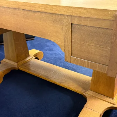 Sale Photo Thumbnail #688: Antique quarter-sawn oak library table featuring a trestle base with scroll-cut feet and paneled sides.