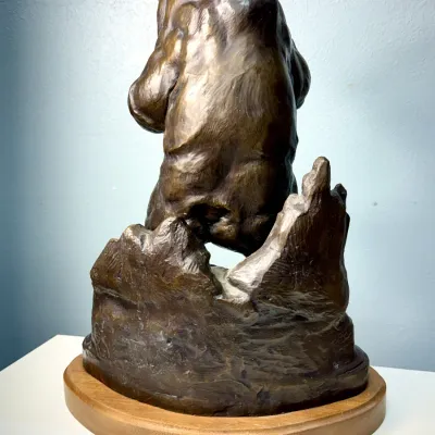 Sale Photo Thumbnail #120: Cast bronze sculpture of a standing bear on a rocky terrain base, mounted on a round wooden display platform.