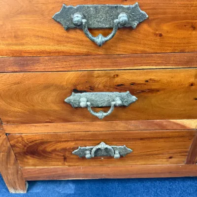 Sale Photo Thumbnail #247: Warm tone wood chest of drawers featuring decorative metal pull handles and visible wood grain details.