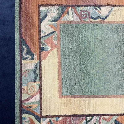Sale Photo Thumbnail #712: Corner detail of a contemporary hand-tufted wool area rug featuring abstract geometric and scroll borders in sage green, terracotta, and beige tones.