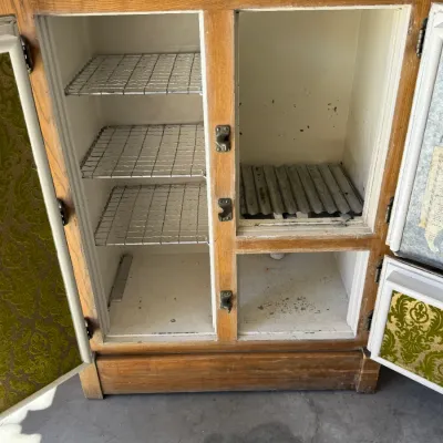 Sale Photo Thumbnail #269: Vintage oak icebox cabinet featuring green damask-patterned interior door linings, wire shelves, and heavy brass hardware.