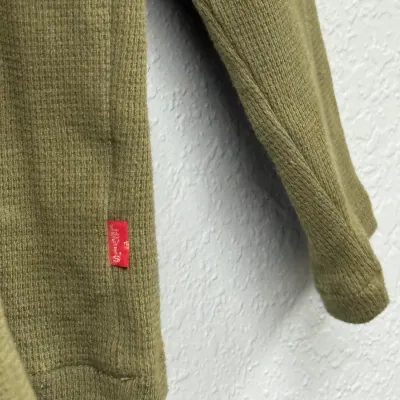 Sale Photo Thumbnail #889: Close-up of an olive green Levi's thermal waffle-knit shirt featuring a signature red logo tab.