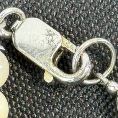 Sale Photo Thumbnail #353: Close-up of a silver lobster claw clasp on a beaded necklace, showing hallmark stampings.