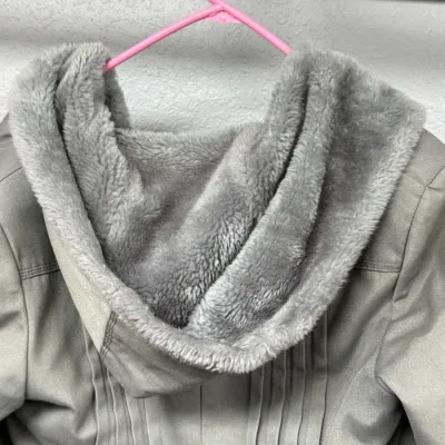 Sale Photo Thumbnail #876: Gray winter jacket featuring a plush faux fur-lined hood, hanging on a pink plastic hanger.