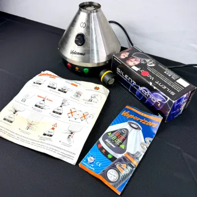 Sale Photo Thumbnail #838: Storz & Bickel Volcano Classic tabletop vaporizer set, including the main unit, instructional manual, product brochure, and a boxed Silent Vapor accessory.