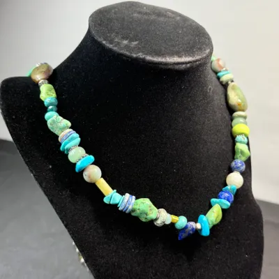 Sale Photo Thumbnail #338: Multicolor beaded gemstone necklace featuring turquoise nuggets, lapis lazuli, and mixed stone beads on a black jewelry bust.