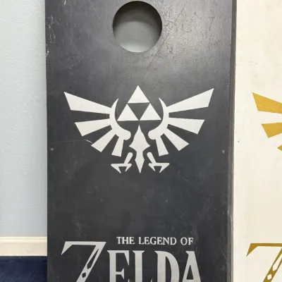 Sale Photo Thumbnail #921: Custom wooden cornhole board featuring The Legend of Zelda logo and Royal Crest graphic.