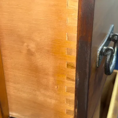 Sale Photo Thumbnail #216: Close-up detail of machine-dovetailed drawer construction on a wooden furniture piece, featuring a dark stained front with metal drop-handle hardware.
