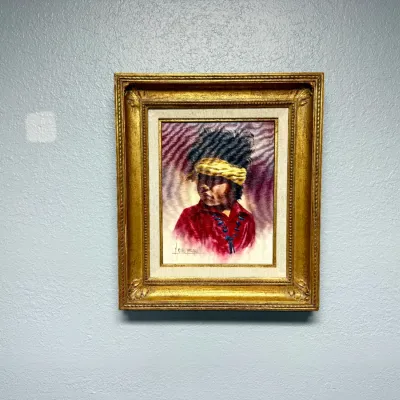Sale Photo Thumbnail #137: Framed vintage oil portrait on velvet depicting a Native American figure wearing a yellow headband, set in an ornate gilded wood frame with a linen liner.