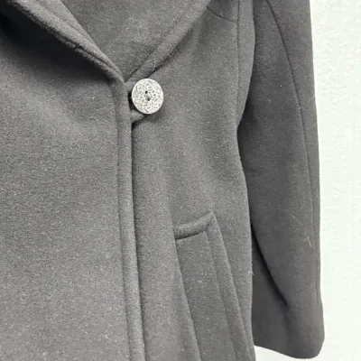 Sale Photo Thumbnail #859: Black wool women's overcoat featuring a wide lapel, a detailed carved decorative button, and front welt pockets.
