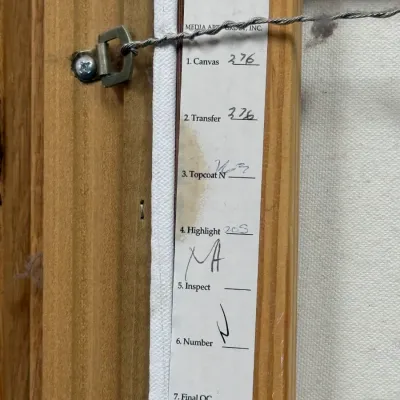 Sale Photo Thumbnail #833: Back of a framed canvas art print showing hanging wire and a Media Arts Group quality control checklist label.