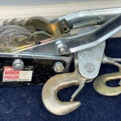 Sale Photo Thumbnail #655: Haul-Master heavy-duty cable winch puller featuring an 8000 lb double-line capacity, steel cable, ratchet mechanism, and dual safety hooks.