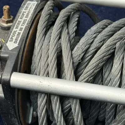 Sale Photo Thumbnail #664: Close-up view of a heavy-duty mechanical winch drum wrapped with braided steel wire cable.