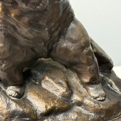 Sale Photo Thumbnail #123: Detailed view of the base and legs of a bronze sculpture, featuring a textured rock-like plinth and a rich dark brown patina.