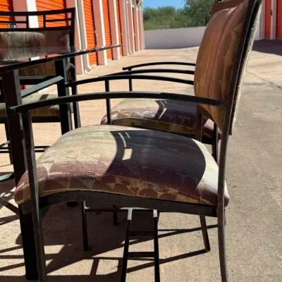 Sale Photo Thumbnail #294: Contemporary wrought iron outdoor armchairs with upholstered patterned cushions, paired with a matching glass-top dining table.