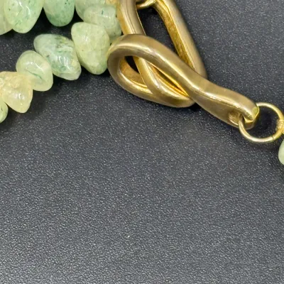 Sale Photo Thumbnail #346: Close-up view of a green aventurine gemstone chip necklace featuring a brass hook-and-eye style clasp.