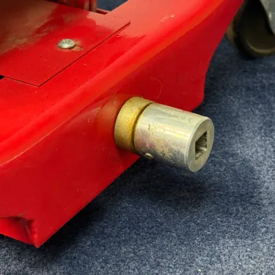 Sale Photo Thumbnail #530: Close-up of a red hydraulic floor jack showing the socket handle attachment connection.
