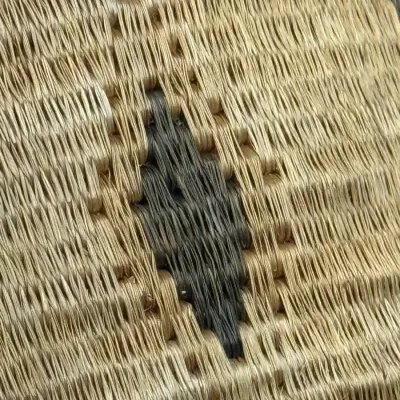 Sale Photo Thumbnail #388: Close-up detail of a woven fiber basket or mat featuring a black diamond motif on a natural tan background.