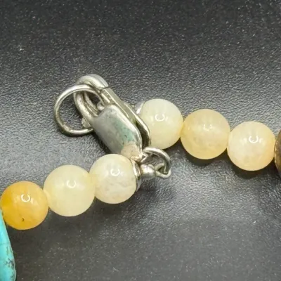 Sale Photo Thumbnail #351: Close-up of a gemstone necklace showing a lobster claw clasp, yellow agate beads, turquoise chips, and a dark stone centerpiece.