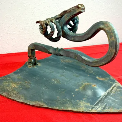 Sale Photo Thumbnail #412: Hand-forged wrought iron flat iron sculpture with a twisted decorative handle and a distressed green patina.
