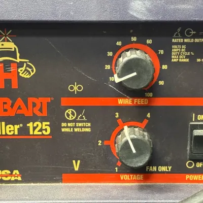 Sale Photo Thumbnail #499: Control panel of a Hobart Handler 125 wire feed welder featuring wire feed and voltage adjustment knobs.
