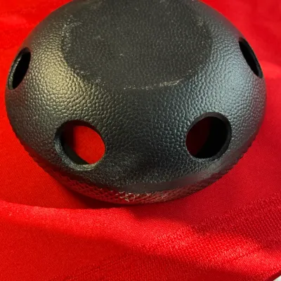 Sale Photo Thumbnail #469: Textured black rubber steering wheel horn cap or center emblem cover with multiple round cutouts, shown on a red fabric background.