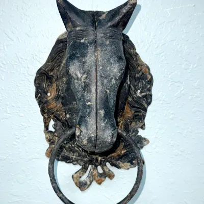 Sale Photo Thumbnail #648: Vintage cast iron horse head door knocker featuring a weathered black finish and a large circular metal ring.