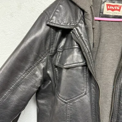 Sale Photo Thumbnail #881: Levi's men's faux leather jacket with an integrated grey knit hoodie lining, featuring chest flap pockets and zip closure.