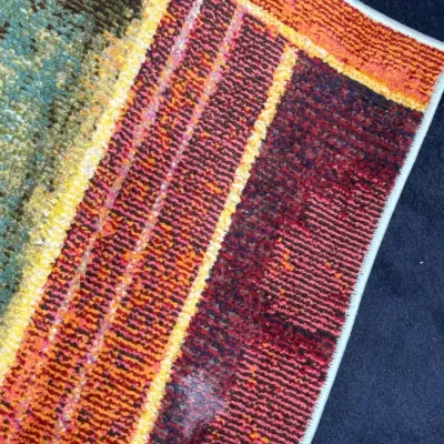 Sale Photo Thumbnail #729: Close-up detail of a modern area rug featuring a colorful striped border in shades of red, orange, yellow, and teal.