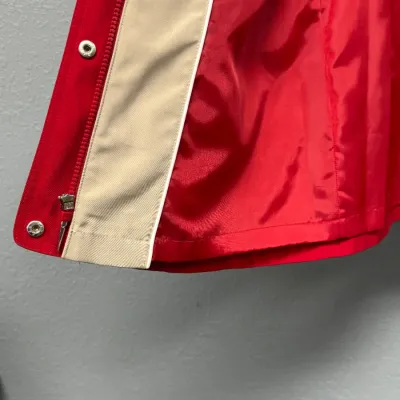 Sale Photo Thumbnail #896: Interior lining and closure detail of a red vintage jacket with a beige inner placket, snap buttons, and a zipper closure.
