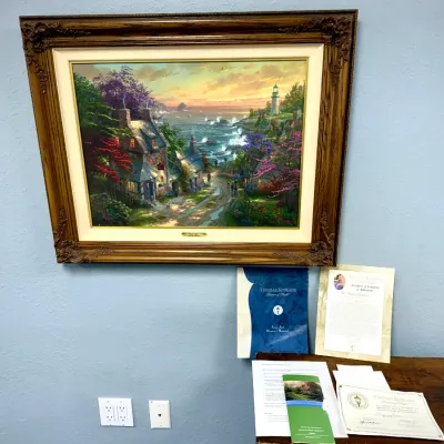 Sale Photo Thumbnail #89: Framed Thomas Kinkade canvas print of a coastal cottage scene with lighthouse, complete with original certificate of authenticity and owner's manual paperwork.