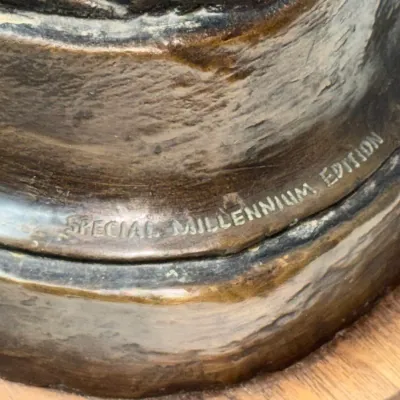Sale Photo Thumbnail #119: Detail of a bronze sculpture base inscribed with "SPECIAL MILLENNIUM EDITION", mounted on a wooden plinth.