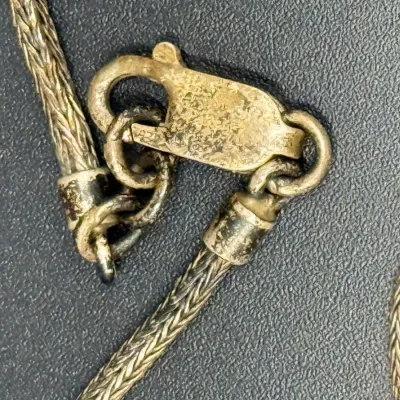 Sale Photo Thumbnail #328: Close-up of a tarnished sterling silver wheat chain necklace showing a lobster claw clasp and end caps.