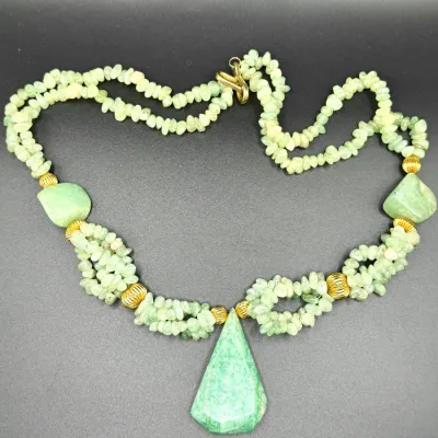 Sale Photo Thumbnail #343: Multi-strand light green gemstone chip necklace featuring gold-tone fluted spacer beads and a large faceted green stone pendant.