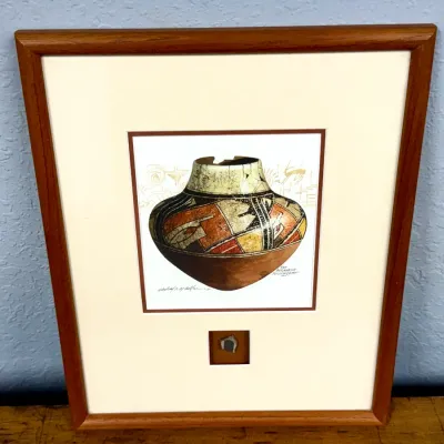 Sale Photo Thumbnail #484: Framed Southwest art print depicting a San Ildefonso polychrome pottery vessel, signed in print and mounted with a small pottery shard fragment below.