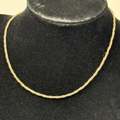 Sale Photo Thumbnail #184: Delicate gold-tone braided chain necklace displayed on a black velvet mannequin bust.
