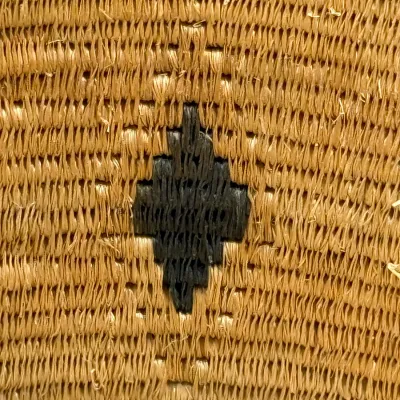 Sale Photo Thumbnail #385: Close-up detail of a hand-woven natural fiber basket featuring a dark geometric diamond motif.