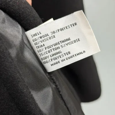 Sale Photo Thumbnail #862: Close-up of a garment care and material label showing a wool-blend shell construction, made in Guatemala.