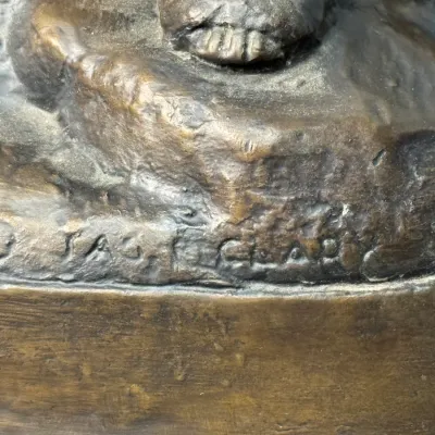Sale Photo Thumbnail #128: Close-up detail of an artist's signature inscribed into the base of a cast bronze sculpture.