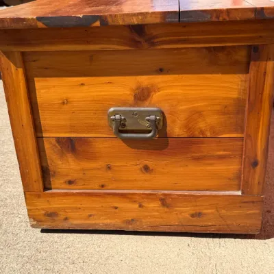 Sale Photo Thumbnail #320: Rustic wooden trunk or chest featuring a natural knotty grain finish and a heavy-duty metal side drop handle.