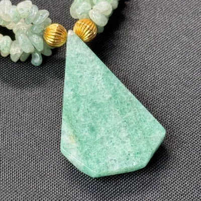 Sale Photo Thumbnail #347: Multi-strand green aventurine chip bead necklace featuring a large geometric slab pendant and ribbed gold-tone spacer beads.