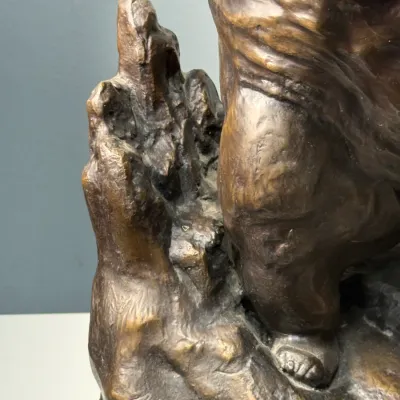 Sale Photo Thumbnail #122: Close-up detail of a patinated bronze sculpture depicting a draped figure on a textured, rocky base.