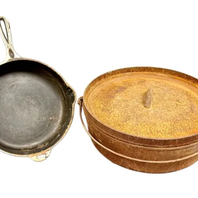 Sale Photo Thumbnail #49: Vintage cast iron skillet alongside a heavily rusted Dutch oven with lid and bail handle.