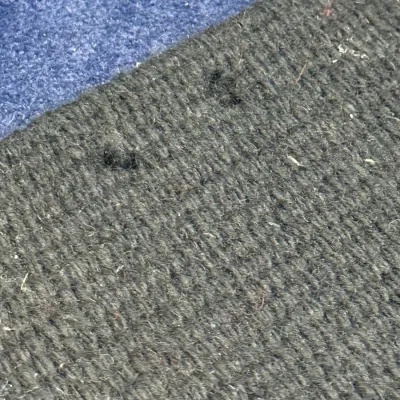 Sale Photo Thumbnail #439: Close-up view of a dark woven rug showing minor wear and loose threads along the edge.