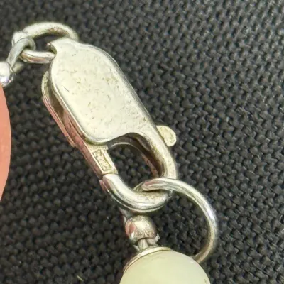 Sale Photo Thumbnail #354: Close-up of a sterling silver lobster claw clasp on a beaded necklace, showing hallmark stamps.