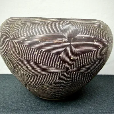 Sale Photo Thumbnail #129: Handcrafted ceramic pot with intricately etched geometric starburst pattern in a dark brown finish.