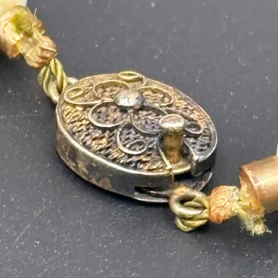 Sale Photo Thumbnail #359: Macro view of a vintage filigree box clasp on a knotted silk cord strand of beads.