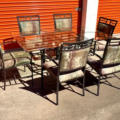Sale Photo Thumbnail #291: Seven-piece dining set including a glass-top table with a dark metal frame and six matching armchairs with patterned fabric upholstery.